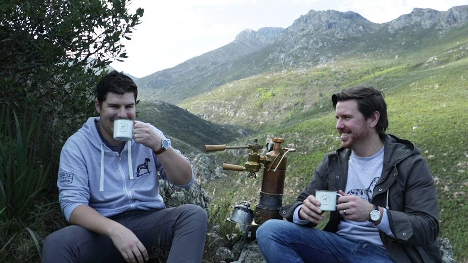 Two men enjoying Terbodore coffee with mountain in background