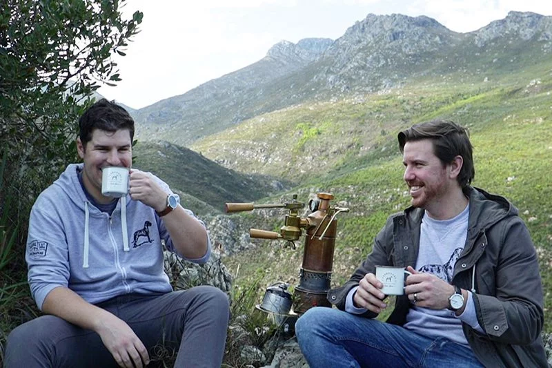 Two men enjoying Terbodore coffee with mountain in background