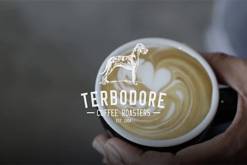 Man holding coffee cup with Terbodore Coffee Roasters logo