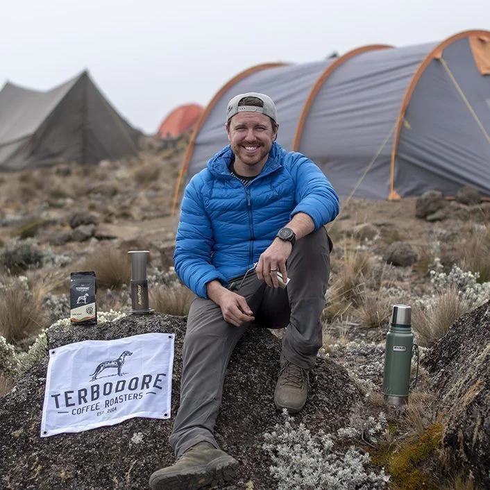 Man sitting on rock smiling, with Terbodore Coffee