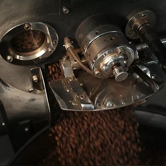 Coffee beans being poured out of a roaster - Terbodore Coffee