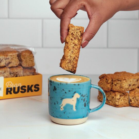 Woamn dunking Bran Rusks into a mug with big dog Terbodore