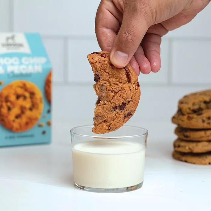 Man dunking Choc Chip Pecan Cookie into a glass of milk Terbodore Pantry